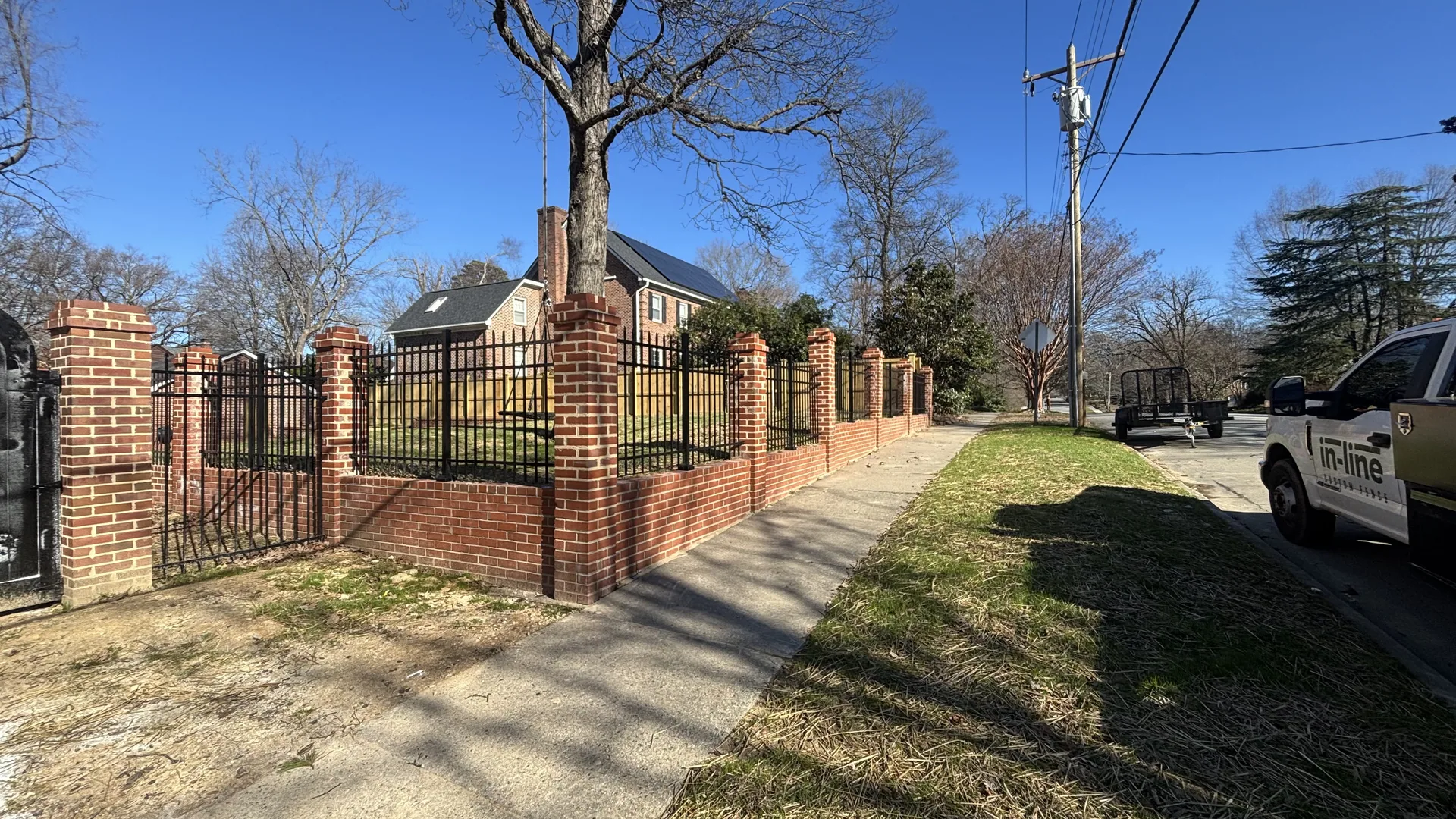 Black metal fence with brick pillars and a gate, installed in Greensboro, NC
